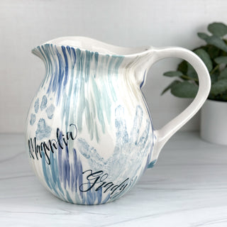 Large pitcher decorated with blue line art and two children's handprints 