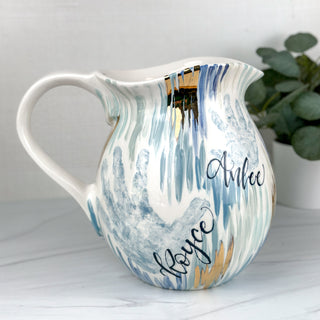 Large pitcher decorated with blue line art and two children's handprints 