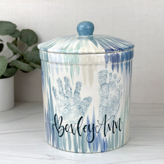 Large jar decorated with blue line art and a child's hand and footprint 