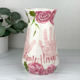 Large vase decorated with pink florals and two children's handprints 