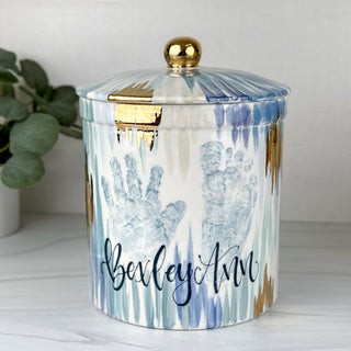Large jar decorated with blue line art with gold and a child's hand and footprint 