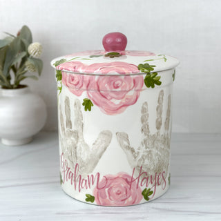 Large jar decorated with pink florals and two handprints 