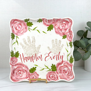 Large square plate decorated with pink florals and two handprints 