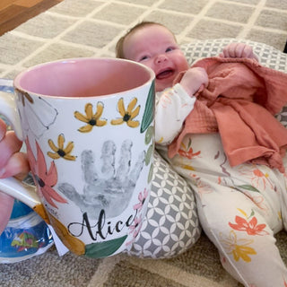 Boho floral mug made with infants handprint held in front of a baby.