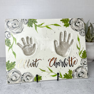 White platter decorated with gray flowers made with two children's handprints. 
