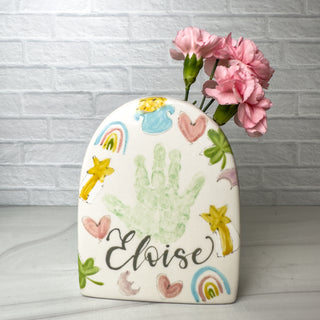 Arched vase decorated with lucky charms themed art, made with a child's handprint.