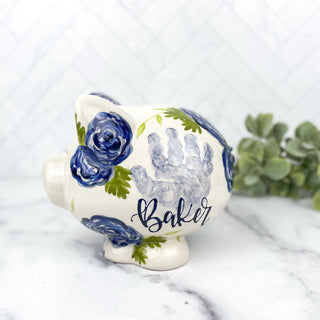 Piggy bank decorated with blue florals and a child's handprint. 