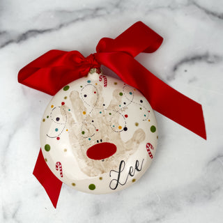 Round ornament decorated with reindeer made from a child's handprint 