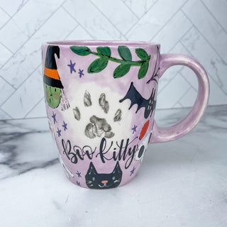 Coffee mug decorated with Halloween art and a paw print 