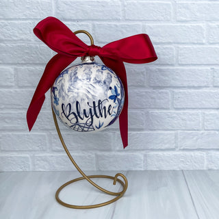 Round ornament decorated with blue chinoiserie and a child's handprint. 
