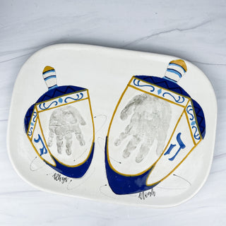 Large platter decorated with two dreidels made with two children's handprints 