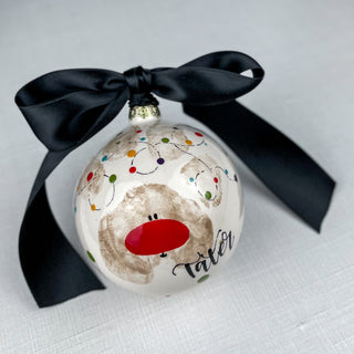 Circular ornament decorated with candy canes and a paw print as a reindeer.
