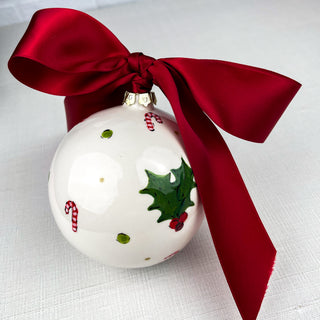 Round ornament decorated with mistletoe, candy canes, and green dots.