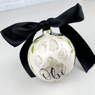 Round ornament decorated with greenery and a paw print