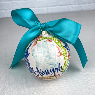 Round ornament decorated with colorful chinoiserie and a child's handprint. 