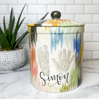 Cookie jar decorated with colorful abstract artwork and a child's hand and footprint.