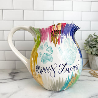 Large pitcher with abstract colorful artwork decorated with a child's handprint and dog's paw print.